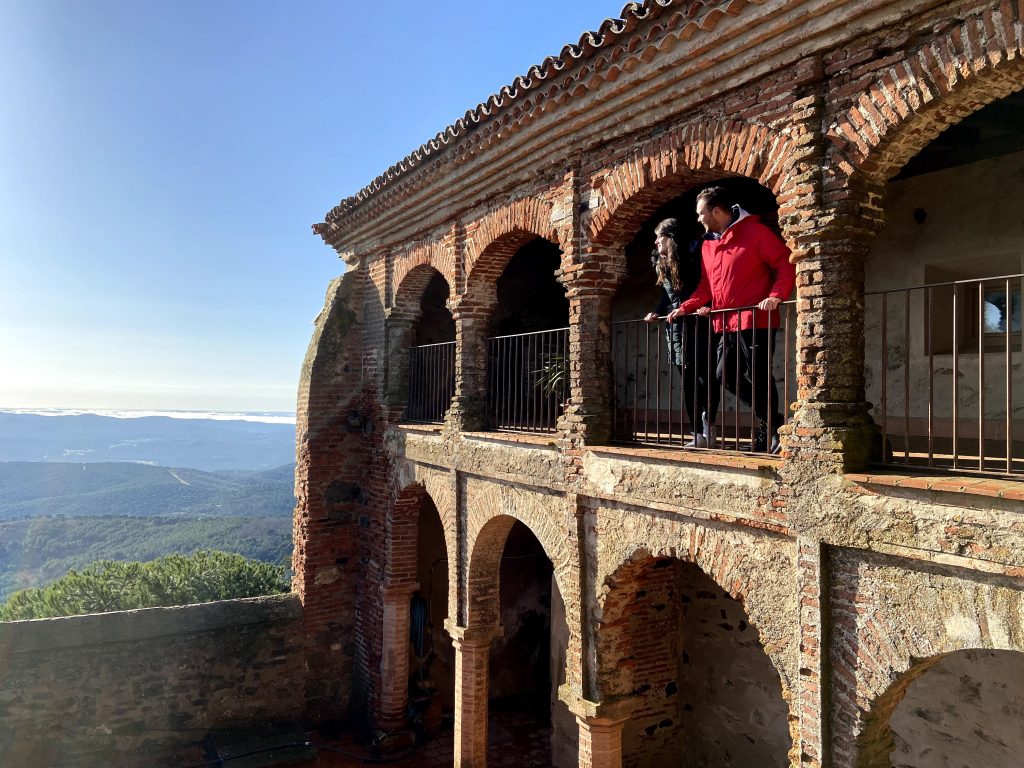 Una persona parada en un balcón con vistas a una montaña.